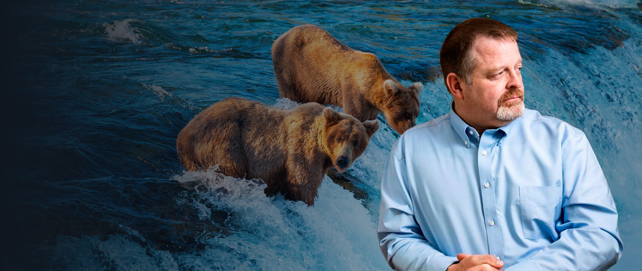 Douglas G. Johnson, Esq. with a photograph of two grizzly bears in the background